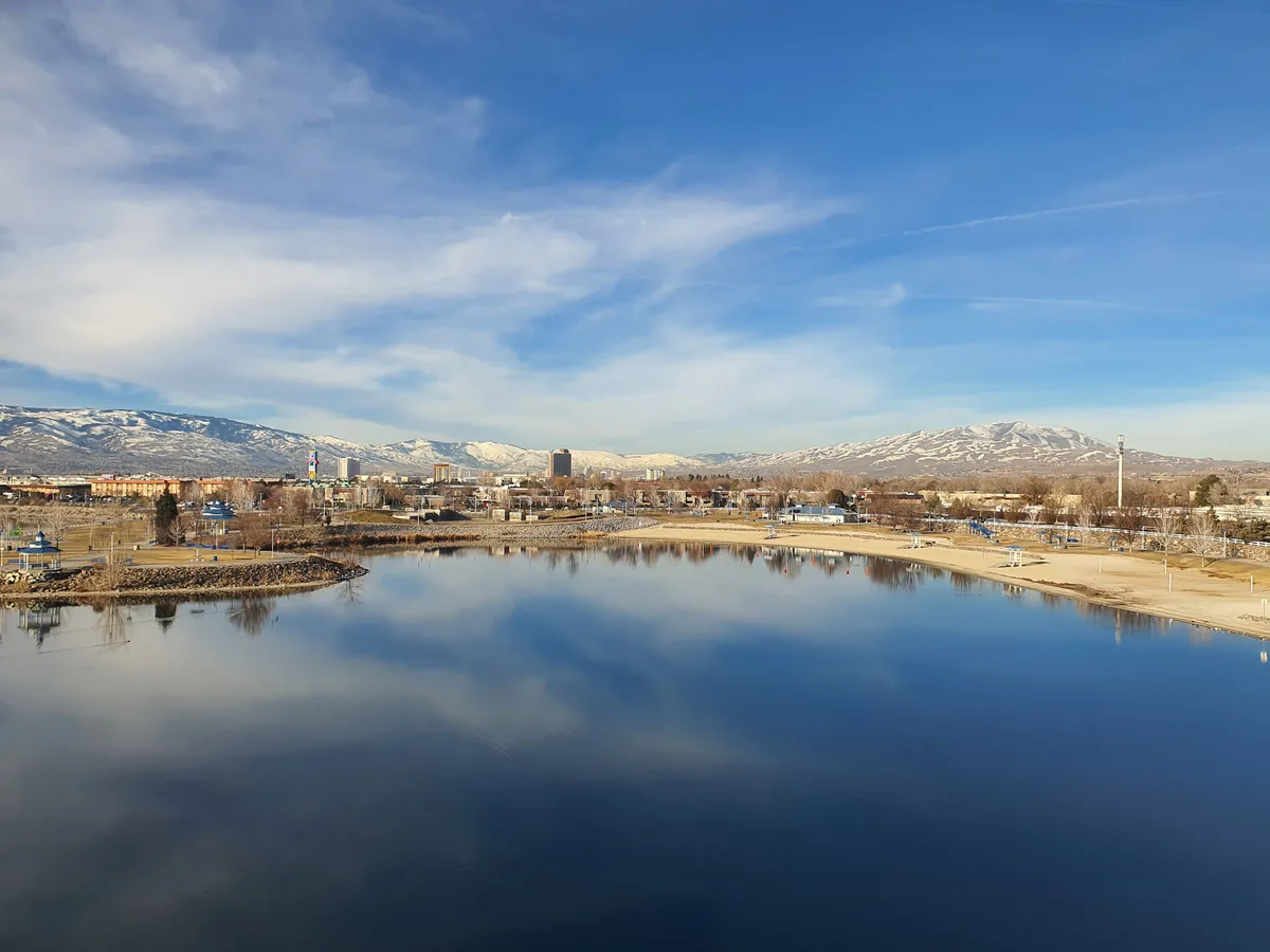 Reno skyline across a lake, with the Sierra Nevada behind